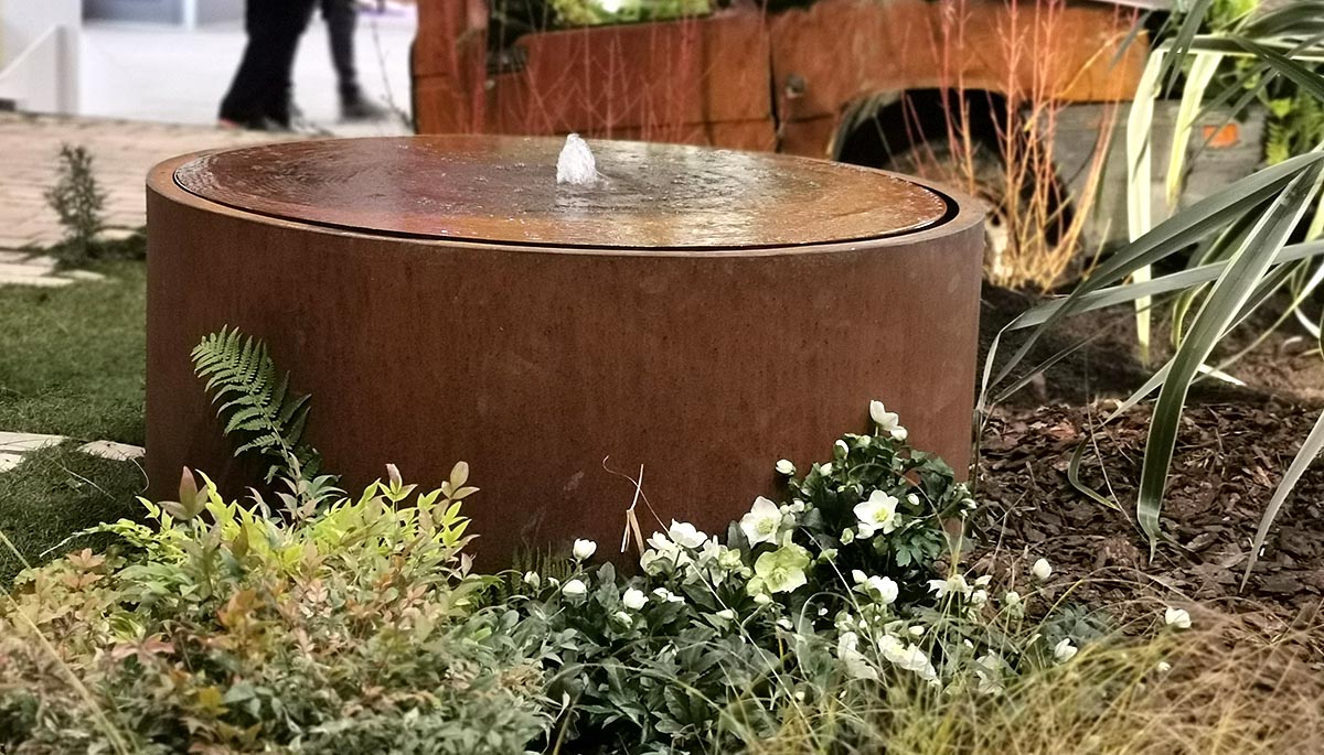 table d'eau en acier corten de couleur rouille au milieu d'un motif paysager