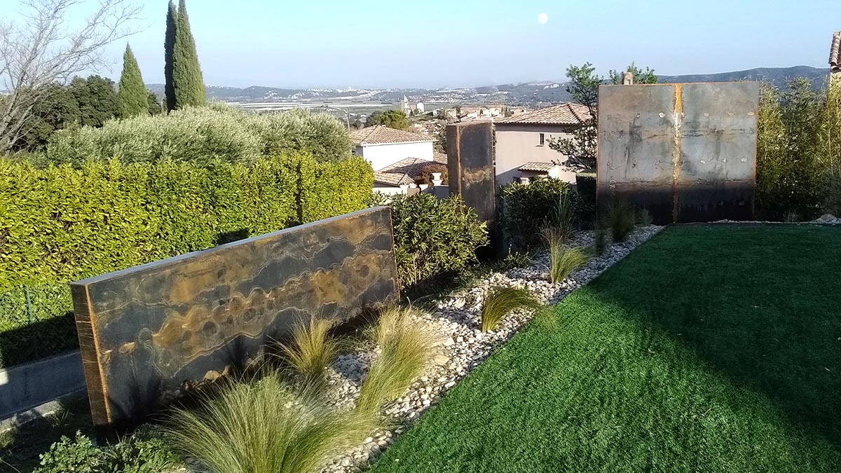 Brise-vue en corten masquant un mur de jardin