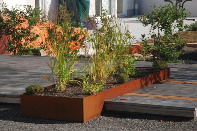 Bac de jardin en acier corten utilisé en carré potager au milieu d'une terrasse de couleur grise