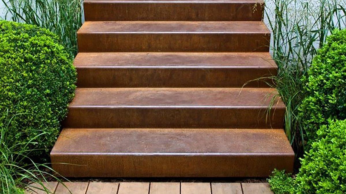 escalier extérieur de jardin en acier corten posé sur une terrasse en bois entre 2 massifs de verdure