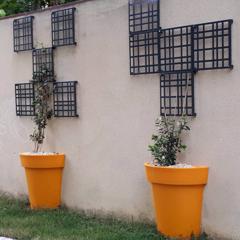 Deux demi-pots de fleurs en plastique de couleur orange plaqués contre un mur blanc