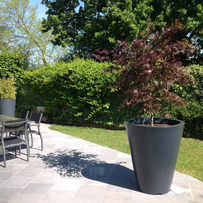 Pot de fleur plastique vase posé sur une terrasse avec un arbuste planté